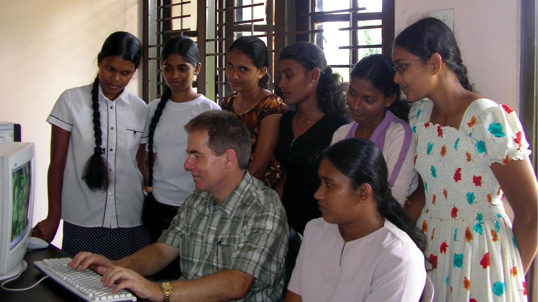 Un volontaire de Projects Abroad montre aux femmes locales comment faire un exercice d'anglais en ligne. Un volontaire du projet d'Autonomisation des Femmes montre aux femmes comment utiliser un ordinateur en Inde.